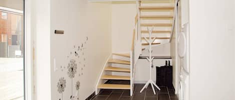 Un interior moderno con una escalera, un perchero y una lavadora.