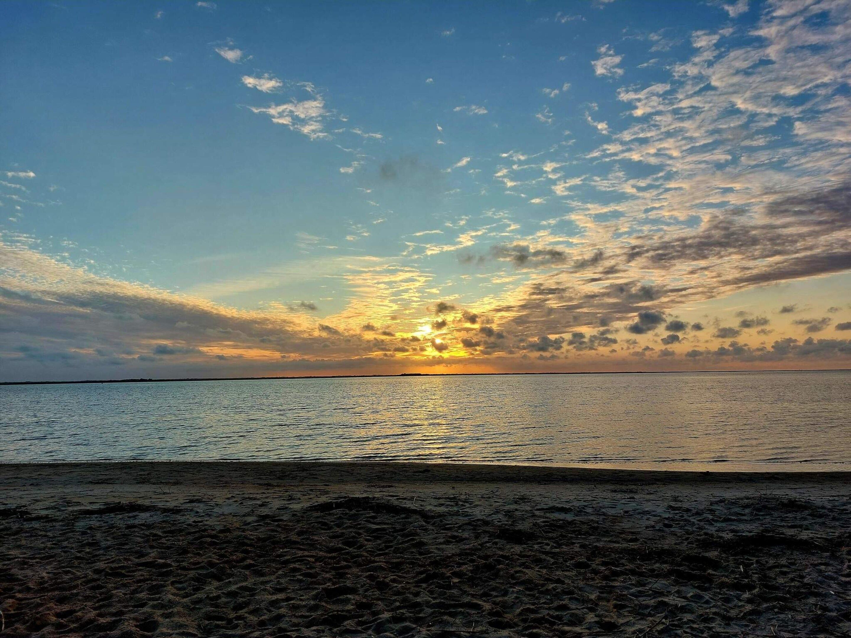 A beach with a sunset over the water.