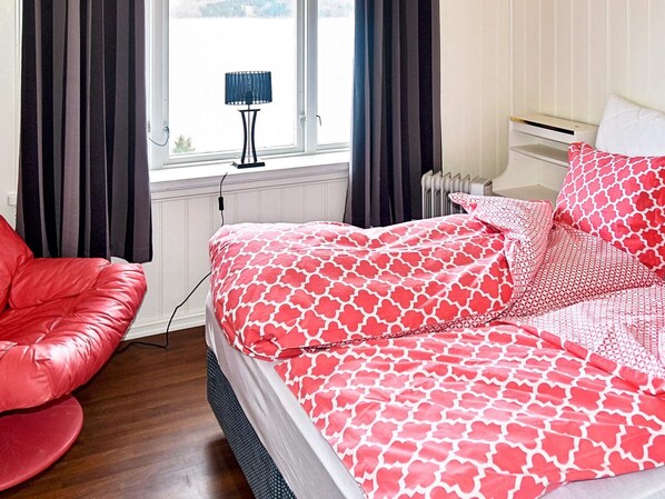 A bedroom with a bed, a red chair, a lamp, and a window. - 4 Star Holiday Home in Folkestad (Volda)