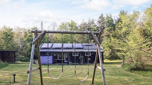A wooden swing set in a grassy area with a house in the background. - 6 Person Holiday Home in Hadsund-by Traum (Hadsund)