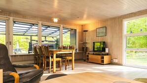 A cozy living room with a wooden dining table, chairs, a sofa, and a television. - 6 Person Holiday Home in Hadsund-by Traum (Hadsund)