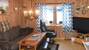 A cozy living room with a sofa, a leather chair, a wooden coffee table, a TV, and a fireplace. - 8 Person Holiday Home in Eidsvag (Molde)