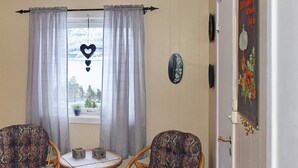 A room with two wicker chairs, a small round table, and a window with curtains. - 8 Person Holiday Home in Eidsvag (Molde)