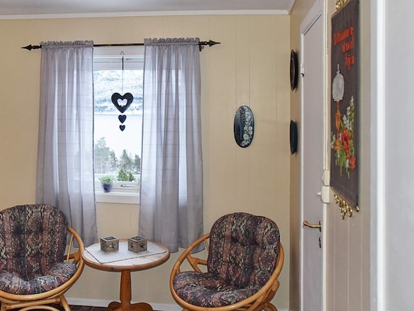 A room with two wicker chairs, a small round table, and a window with curtains.