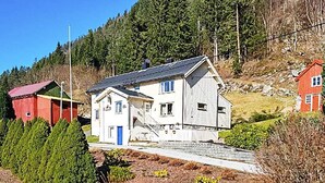 A two-story house with a red barn, a blue door, and a staircase leading to the upper floor. - 8 Person Holiday Home in Eidsvag (Molde)