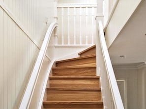 Un escalier en bois avec des rampes blanches et un mur blanc.