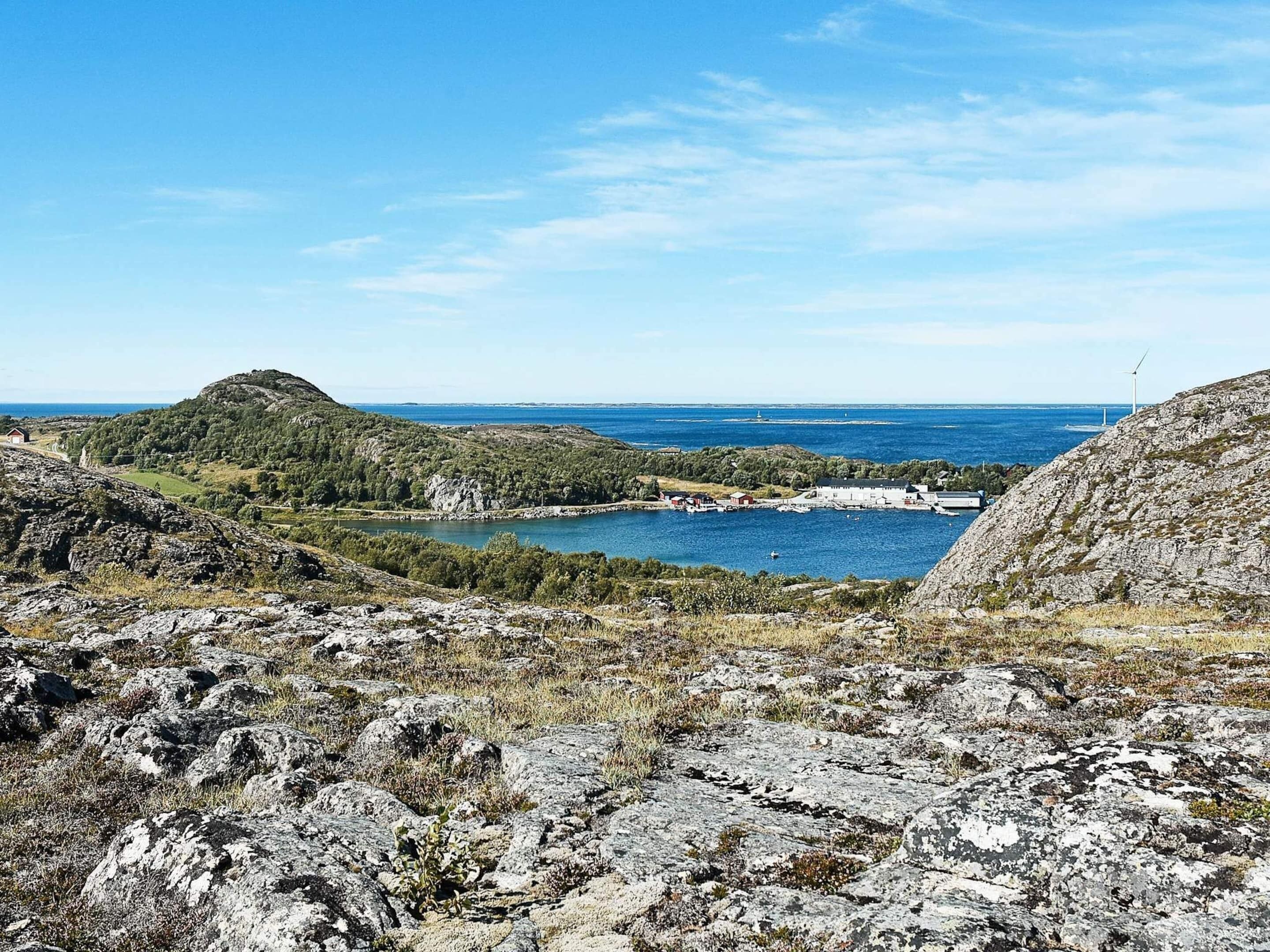A coastal landscape with rocky terrain, a small settlement, and a body of water.