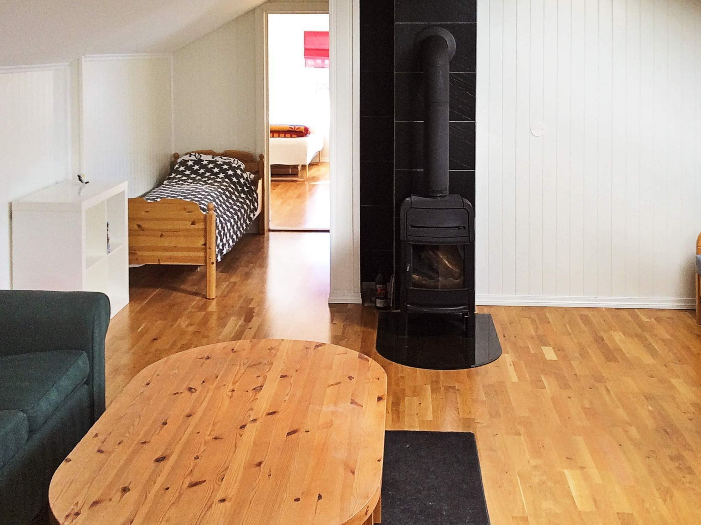 A cozy room with a bed, a table, a sofa, and a wood-burning stove.