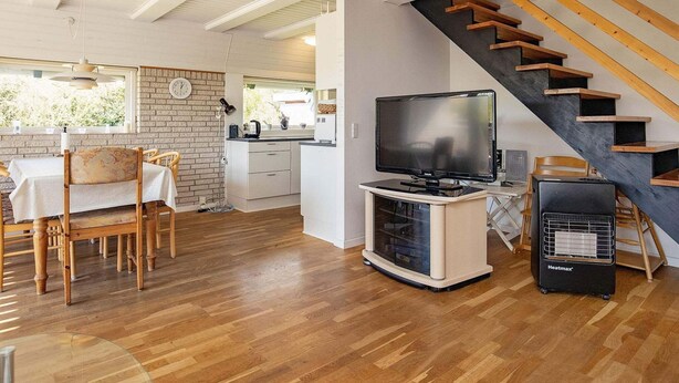 A modern living room with a wooden floor, a dining area with a table and chairs, a kitchen in the background, and a staircase with wooden steps. - 6 Person Holiday Home in Hurup Thy-by Traum (Hurup Thy)