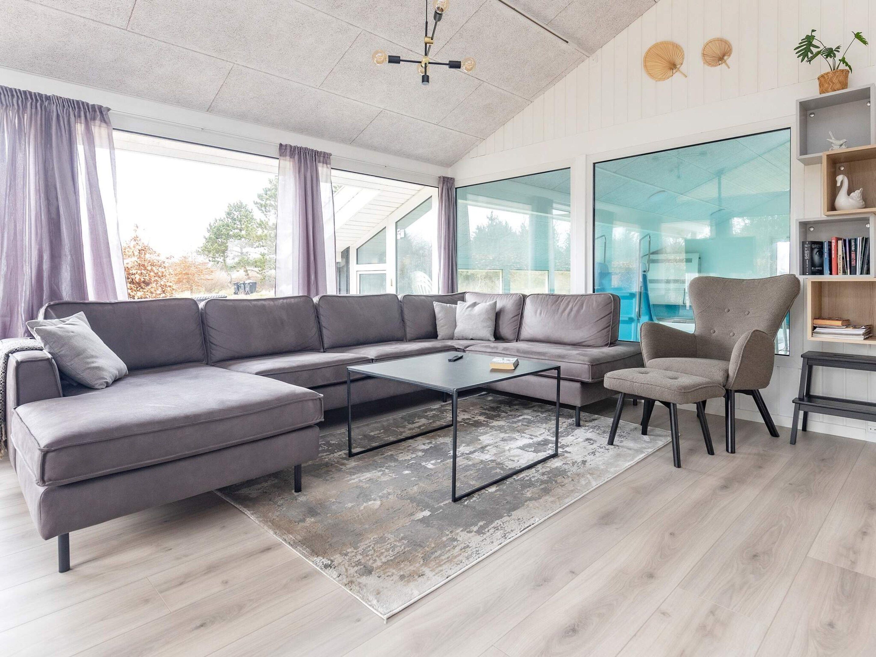 A modern living room with a sectional sofa, a coffee table, a chair, and a bookshelf.