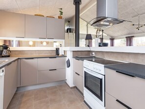 A modern kitchen with a built-in oven, a stove, and a large window.