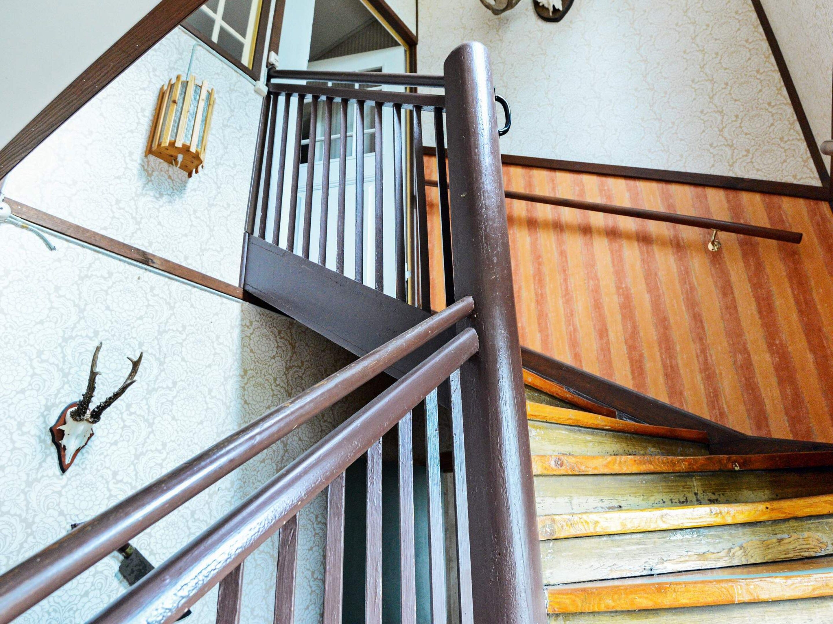 A wooden staircase with metal railings and a patterned wall.