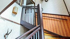 Eine Holztreppe mit Metallgeländern, einer gemusterten Wand und einem dekorativen Wandbild.