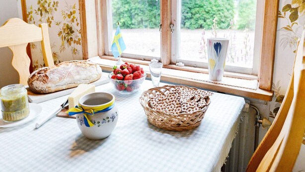 Ein Tisch mit Brot, Erdbeeren, einer Schüssel mit Beeren und einer Tasse, sowie einer Flagge.
