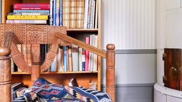 A room with a wooden bed, a bookshelf with books, and a patterned blanket.