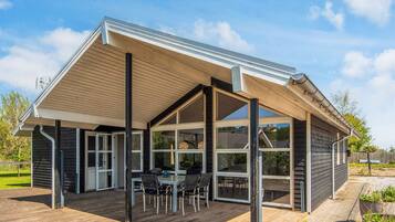 A modern house with a covered patio, large windows, and a wooden deck.