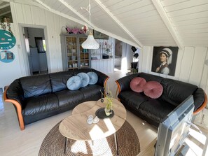 A living room with two black leather sofas, a round wooden coffee table, and a television. - 4 Star Holiday Home in Sydals (Sydals)