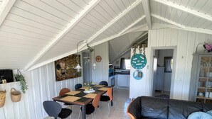 A dining area with a table and chairs, a black leather sofa, and a kitchen in the background. - 4 Star Holiday Home in Sydals (Sydals)