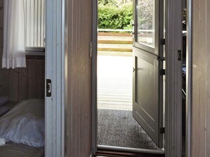 An open door leading to a wooden deck with a bench, a small rug, and a view of greenery. - 4 Star Holiday Home in Sydals (Sydals)