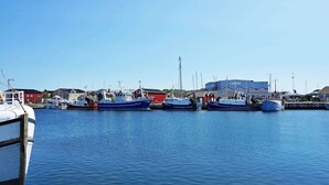 Ein Yachthafen mit mehreren angedockten Booten, ein großes Gebäude im Hintergrund und ein klarer, blauer Himmel.