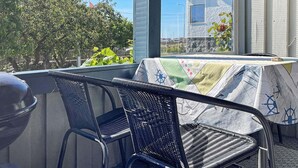Ein Balkon mit Korbstühlen und einem Tisch, bedeckt mit einer gemusterten Tischdecke.
