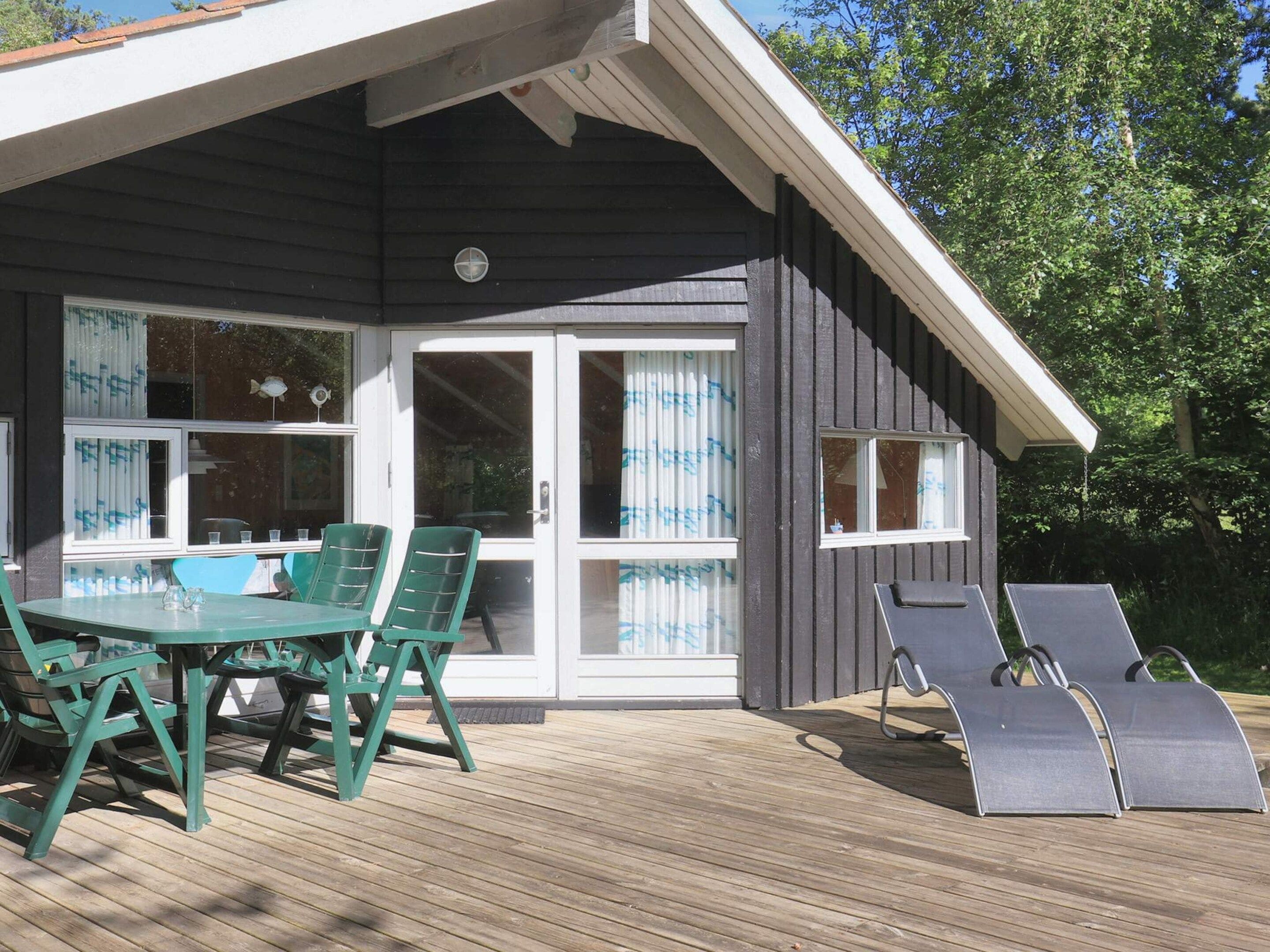 A covered outdoor area with a table and chairs, a sliding glass door, and a deck.