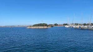 A marina with boats docked, a rocky breakwater, and a clear blue sky.