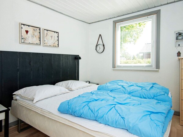 Un dormitorio con una cama, una ventana y dos relojes en la pared.
