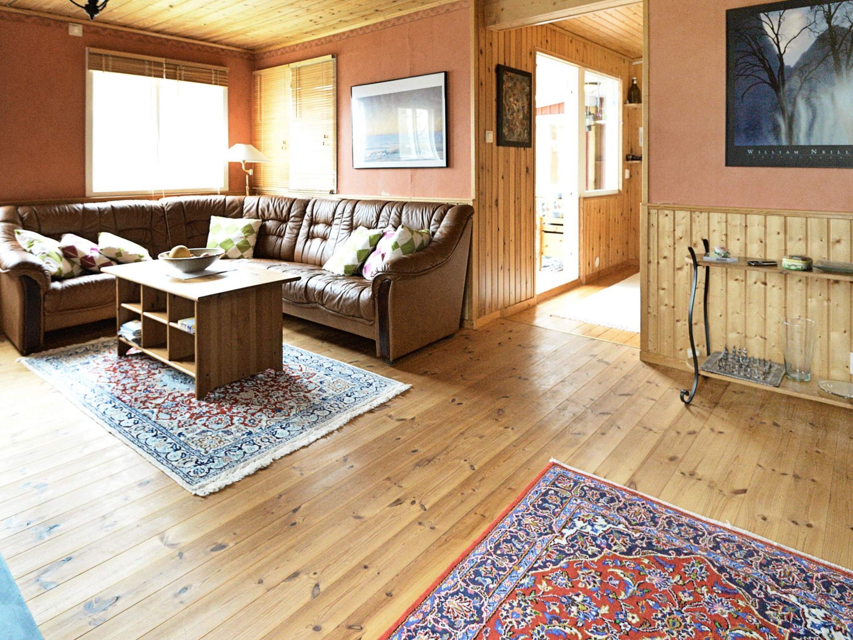 Ett mysigt vardagsrum med en soffa i läder, ett soffbord i trä och en mönstrad matta.