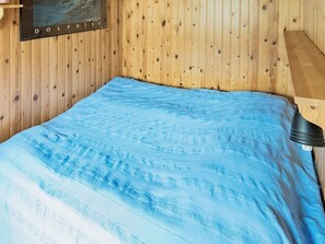 A room with wooden walls, a bed with a blue blanket, and a poster on the wall. - 7 Person Holiday Home in Allingsas, Sverige (Alingsas)
