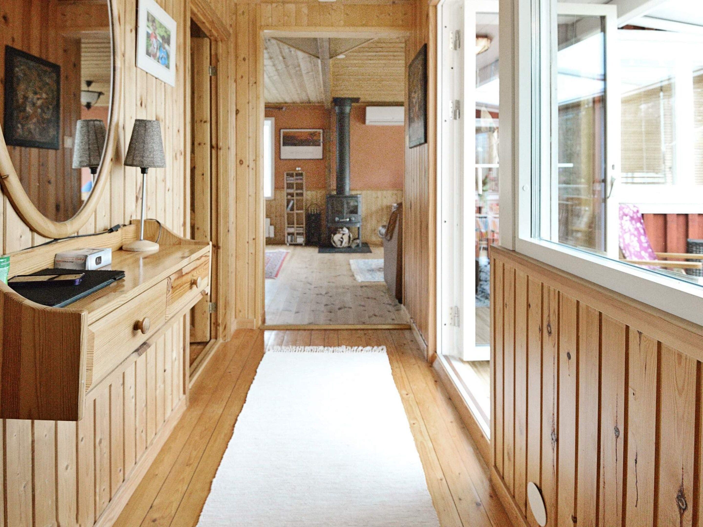 A wooden interior with a fireplace, a mirror, and a window.
