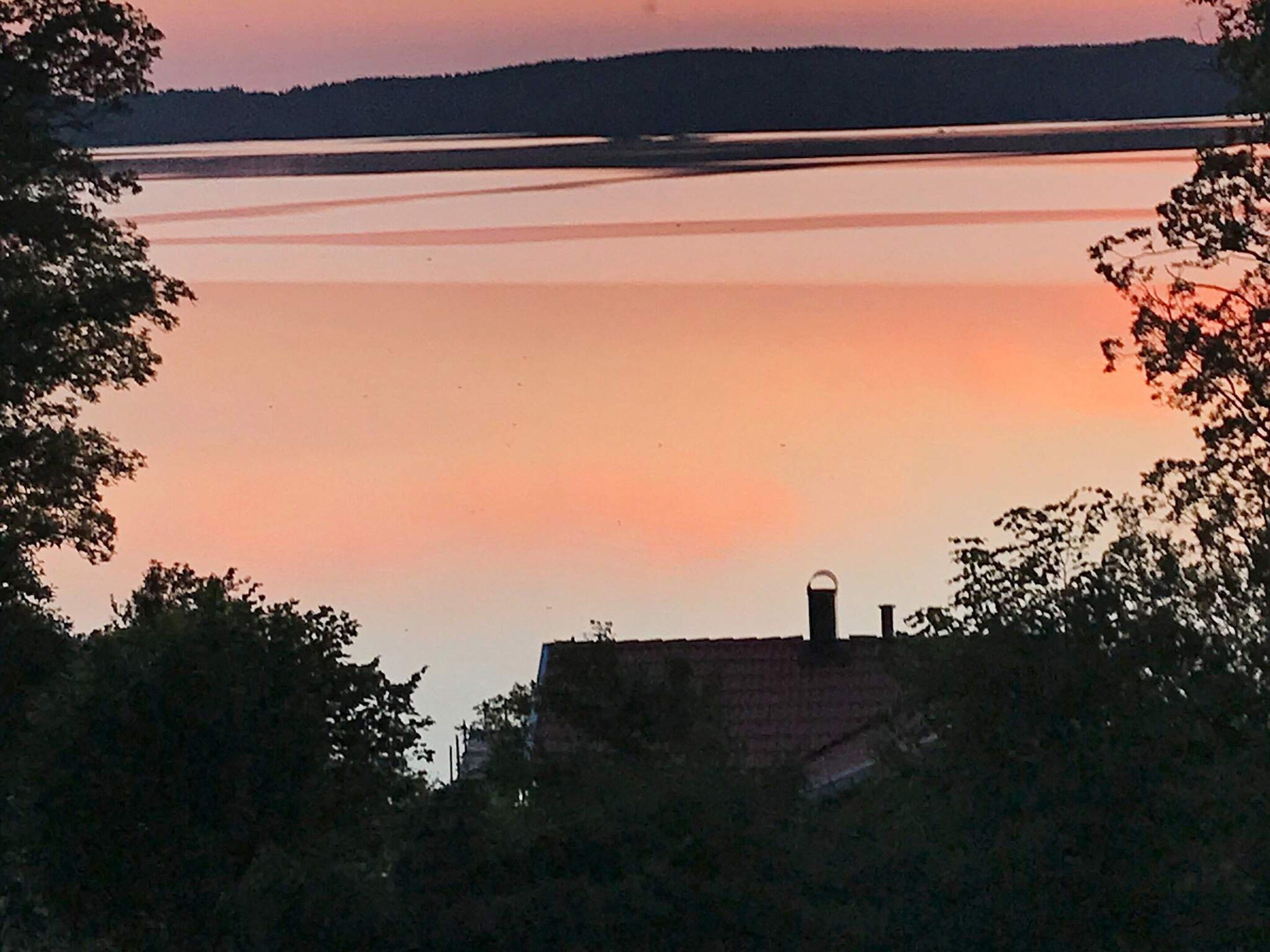 A serene lakeside view with a house in the foreground and a distant shoreline.