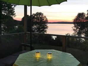 A balcony with a table and two candles, overlooking a calm body of water and trees during sunset. - 7 Person Holiday Home in Allingsas, Sverige (Alingsas)