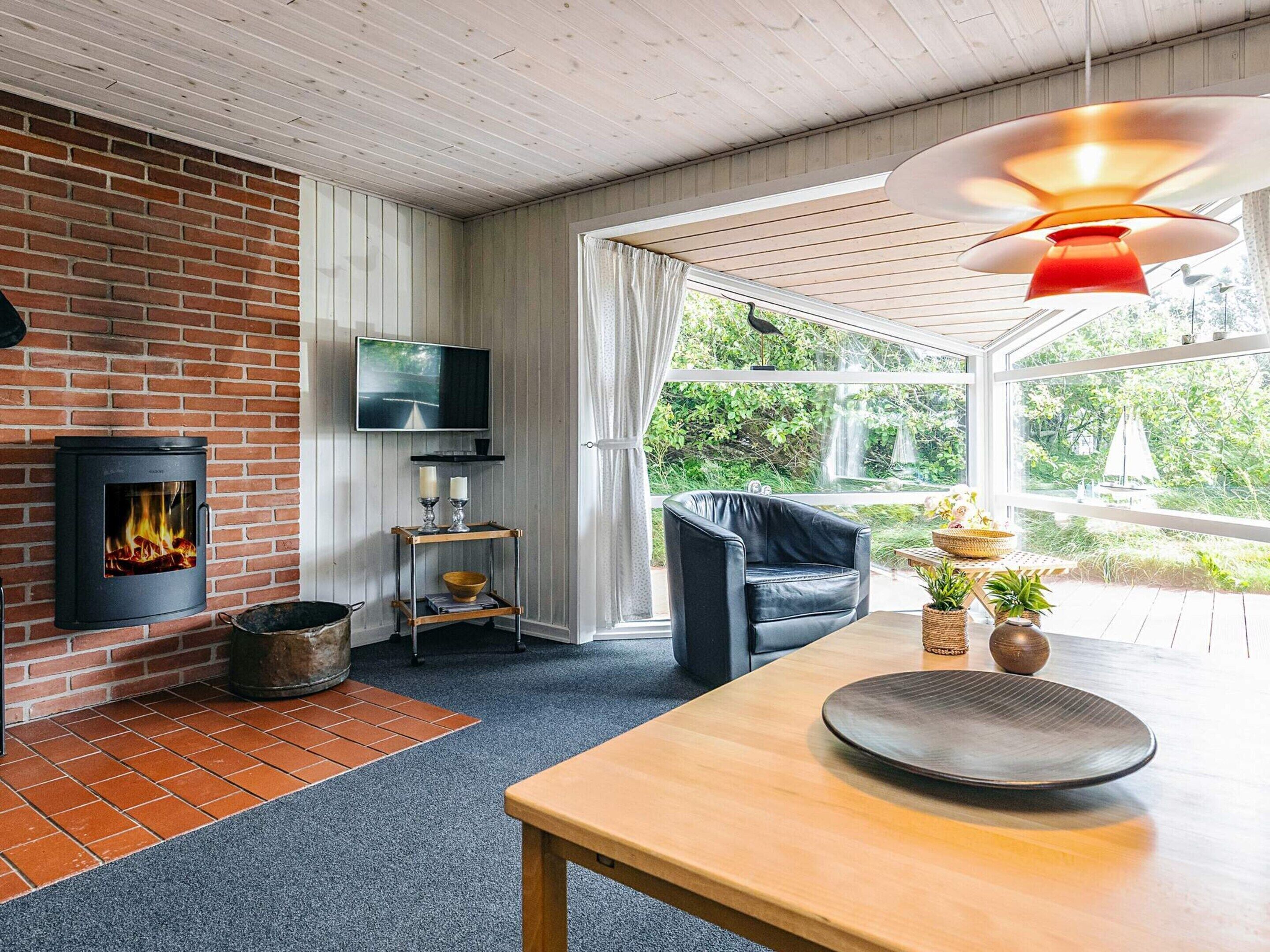 A cozy living room with a fireplace, a television, and a view of the outdoors.