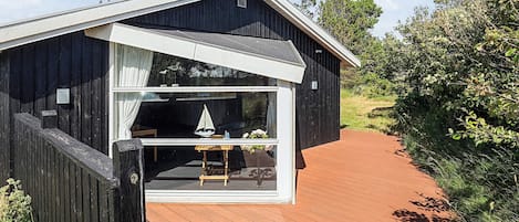 A wooden cabin with a large window, a small table, and a chair inside.
