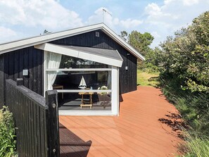 A wooden cabin with a large window, a small table, and a chair inside.