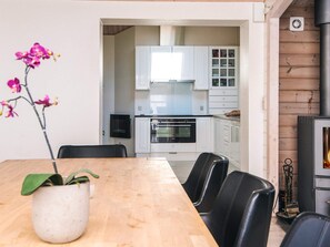 A modern kitchen with white cabinets, a black countertop, and a wood-burning stove. - 4 Star Holiday Home in Juelsminde (Juelsminde)