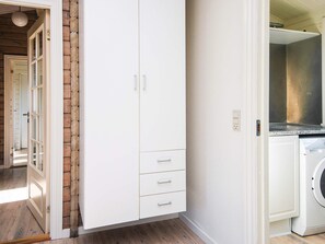 A laundry room with a washing machine, a white cabinet with drawers, and a wooden floor. - 4 Star Holiday Home in Juelsminde (Juelsminde)