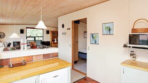 Una cocina compacta con armarios de madera, un microondas integrado y un pequeño comedor.