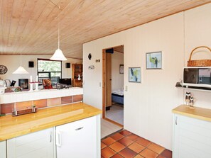 A compact kitchen with a wooden countertop, white cabinets, and a tiled floor.