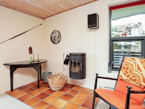 Une pièce avec une cheminée, une table avec des bougies, une chaise, un panier et une fenêtre donnant sur un beau paysage.