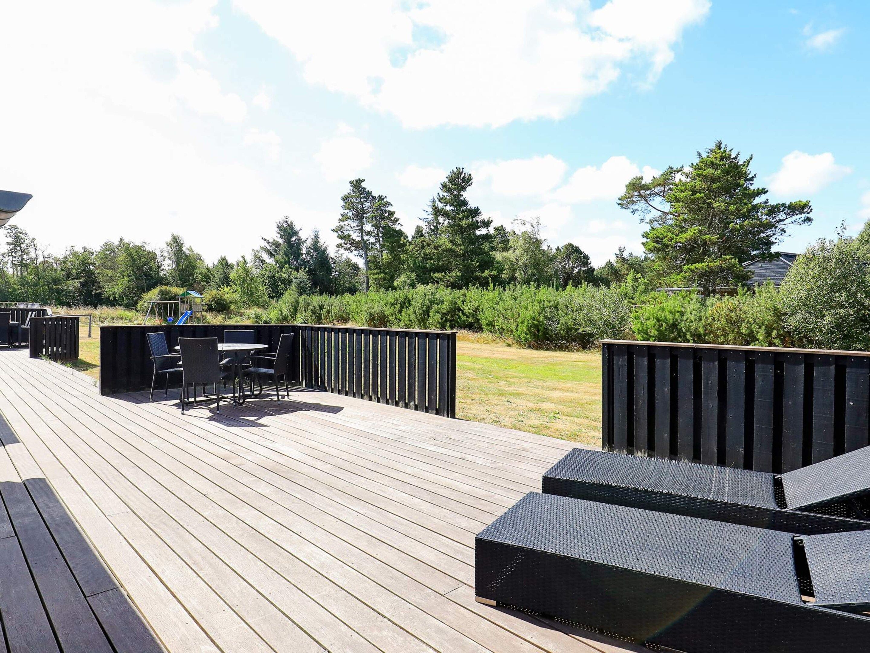 A wooden deck with outdoor furniture and a play area.