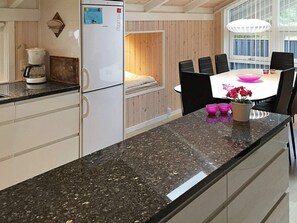 A modern kitchen with a built-in refrigerator, a coffee maker, and a dining area with a table and chairs. - 9 Person Holiday Home in Jerup (Jerup)
