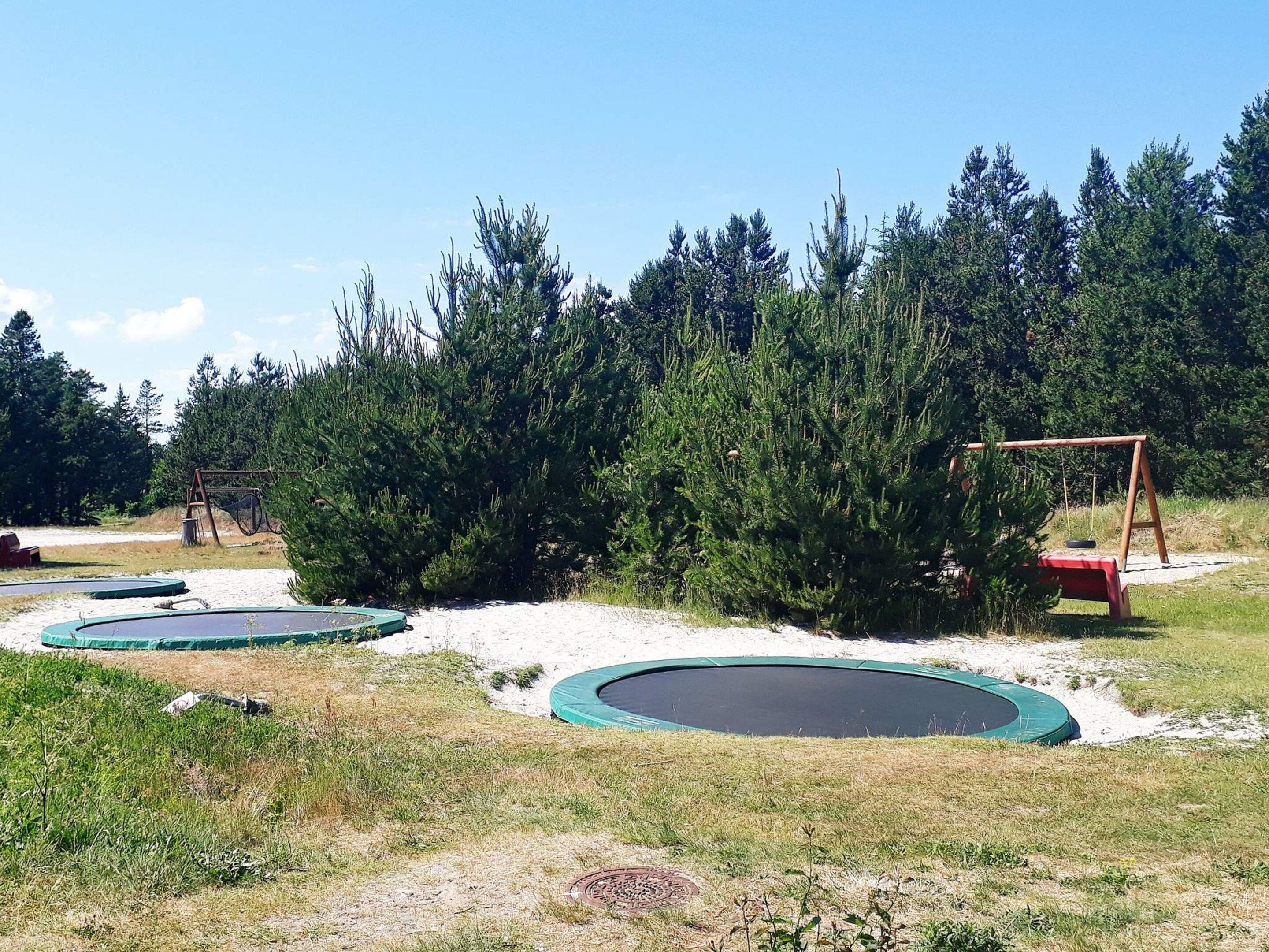 A playground with multiple trampolines and a swing set.