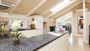 A modern kitchen with a granite countertop, wooden ceiling beams, and a large window. - 9 Person Holiday Home in Jerup (Jerup)