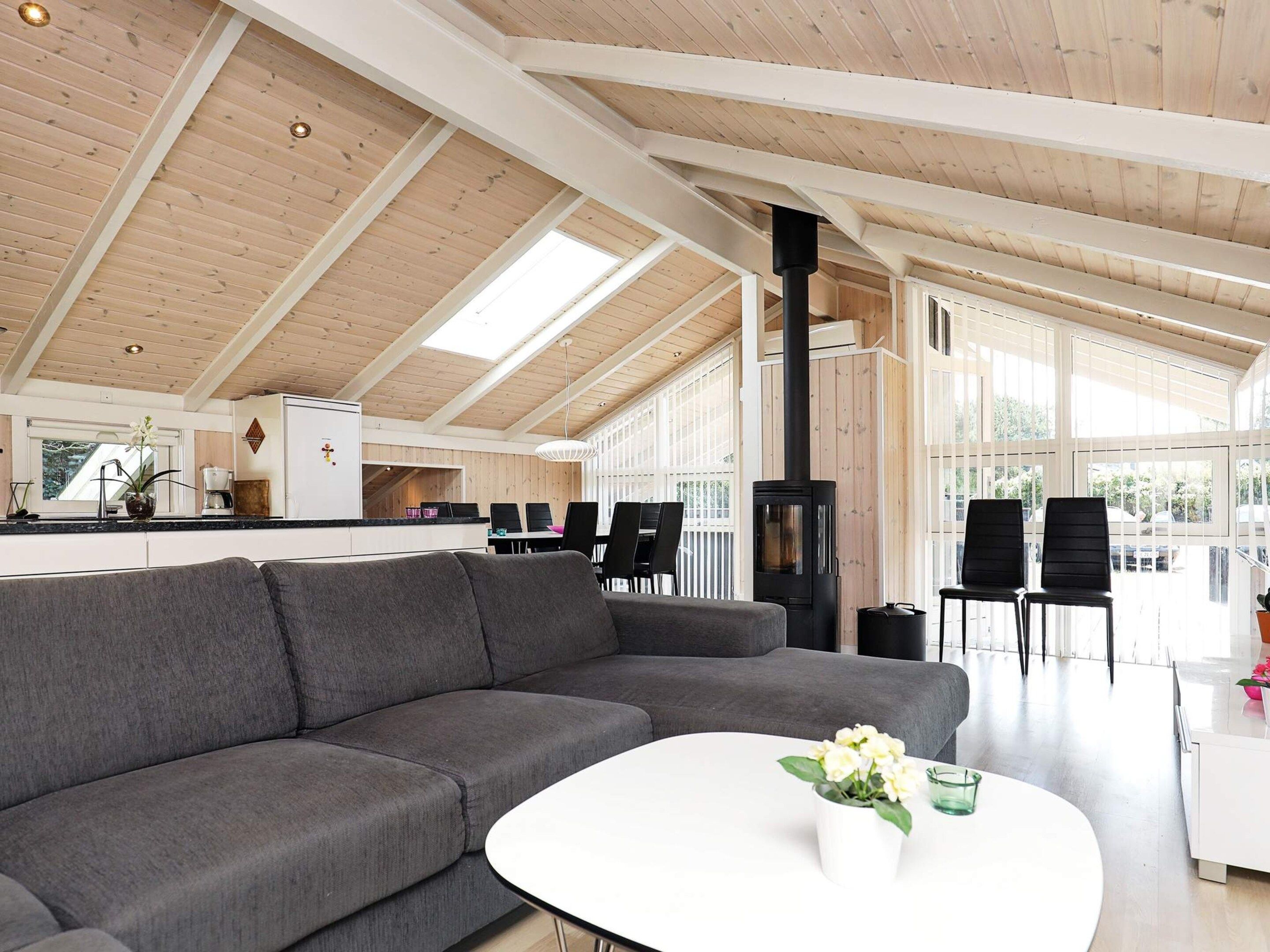 A modern interior with a grey sofa, a white coffee table, and a black wood-burning stove.