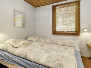 A bedroom with a bed, a window with blinds, a wall-mounted light, and a framed picture. - 8 Person Holiday Home in Hadsund (Hadsund)