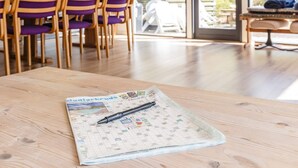 A table with a board game and a pen, wooden chairs, and a bench in a room with large windows. - 8 Person Holiday Home in Hadsund (Hadsund)