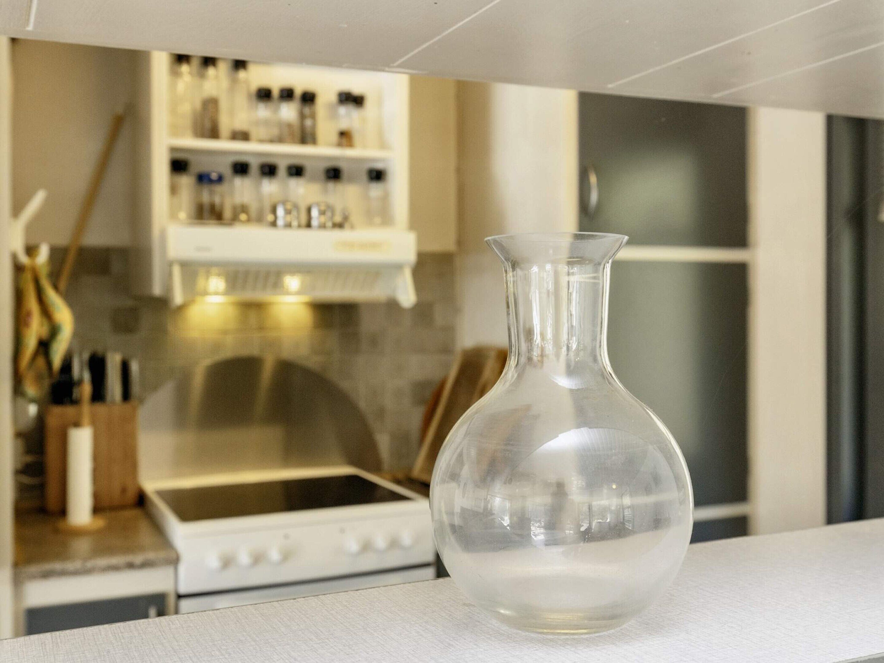 A kitchen with a white countertop, a clear glass vase, and a stove.