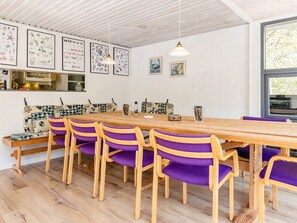 A dining area with a wooden table and purple chairs, white walls with framed botanical prints, and a window with a view of trees. - 8 Person Holiday Home in Hadsund (Hadsund)